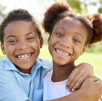 Portrait Of Brother And Sister Relaxing In Park Together