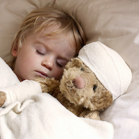 boy and teddybear in bed, with teddy bandaged