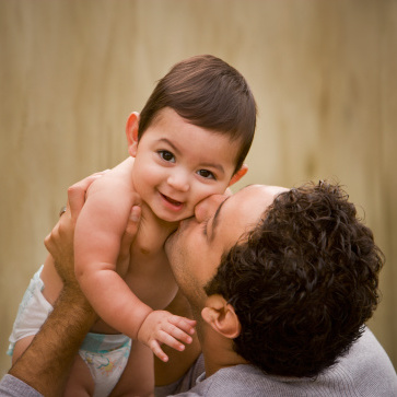 Hispanic father kissing baby